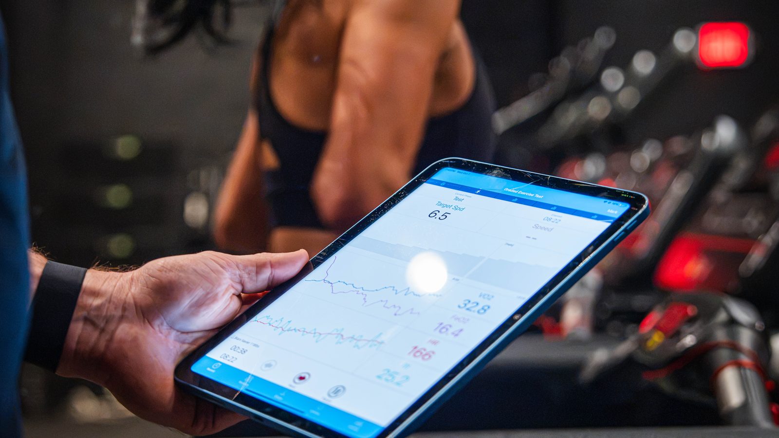A client in the mask on the treadmill, her results on the tablet in front of her